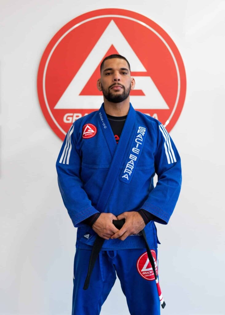 Professor Seidler Rodrigo posing in front of Gracie Barra logo