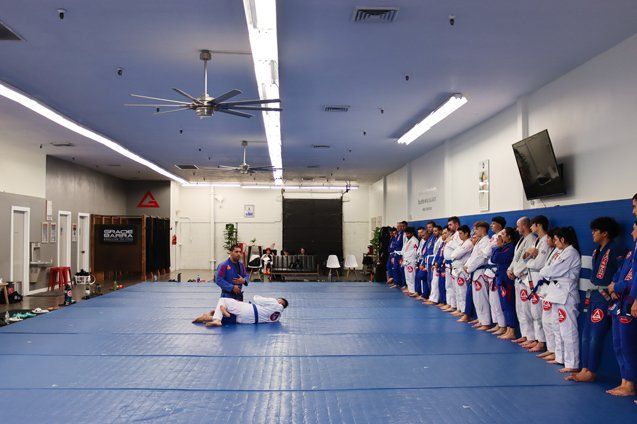 Head Prof. Rodrigo teaching Jiu Jitsu while students watch standing.