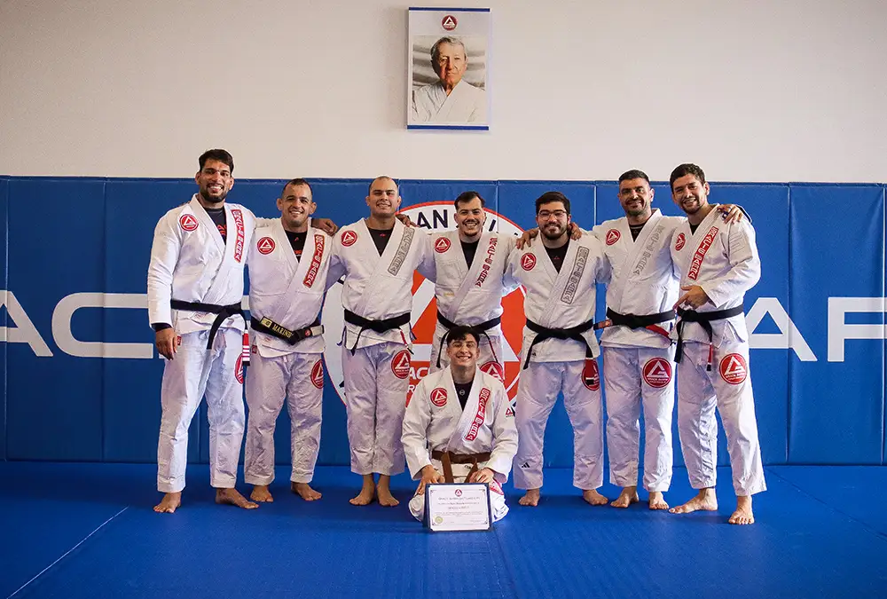Gracie Barra black belts standing behind a newly promoted brown belt holding his certificate