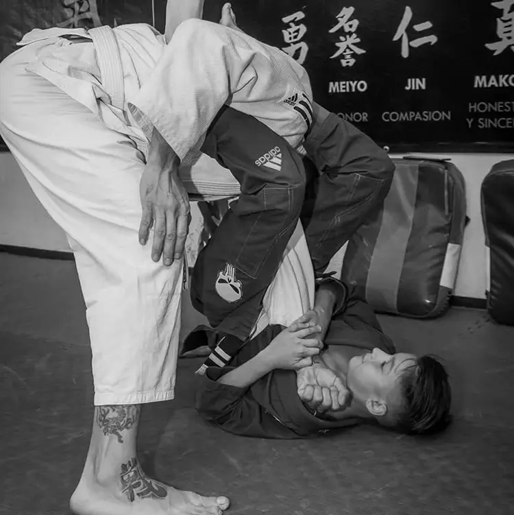 Black and white photo of Jiu-Jitsu training under a banner of martial arts values: honor, compassion, and honesty